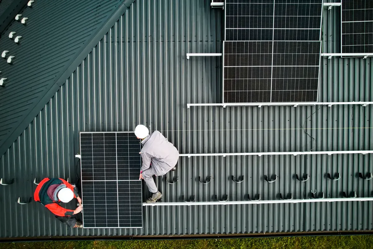 Dos instaladores colocando un panel solar sobre una cubierta metálica en Guadalajara